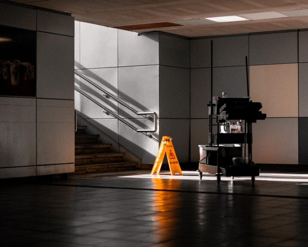 Janitorial cart and wet floor sign in an empty office lobby after hours.